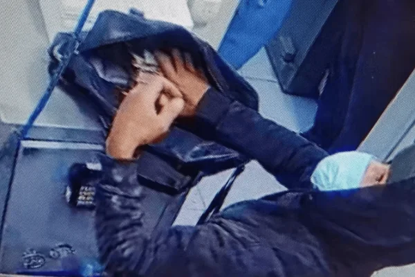 Imagem colorida de um homem colocando dinheiro em uma bolsa durante um assalto à banco - Metrópoles