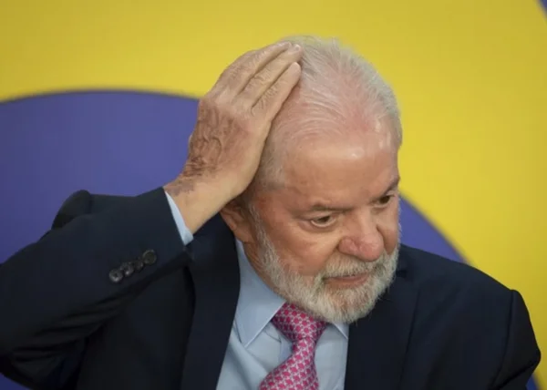 Lula com a mão na cabeça, sob fundo amarelo e azul -- Metrópoles