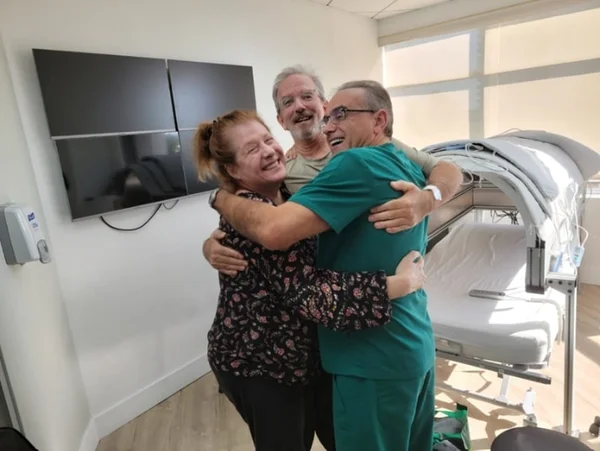 Scott Miller e sua esposa sáo abraçados pelo médico Marc Abreu - Metrópoles