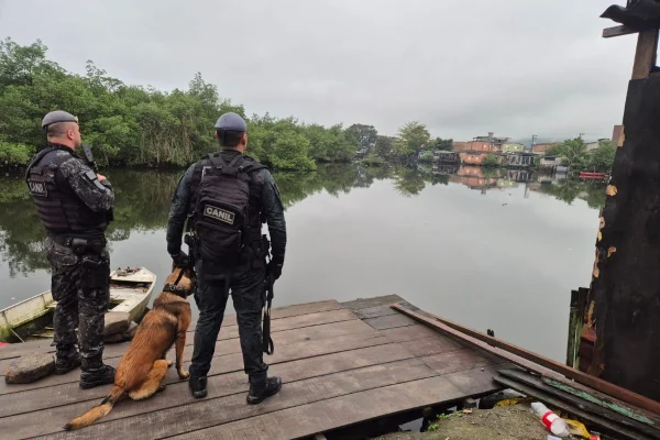Foto colorida de dois policiais militares em cumprimento a mandado na Baixada Santista.