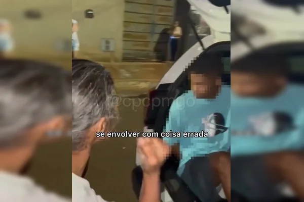 Imagem colorida de mulher em pé e homem dentro de viatura