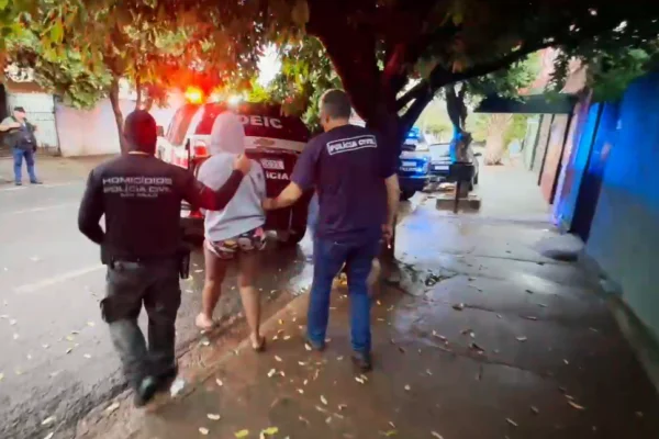 Imagem colorida de policiais conduzindo uma pessoa presa para uma viatura. Metrópoles