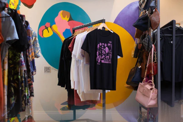 Camisetas penduradas em arara no fundo colorido
