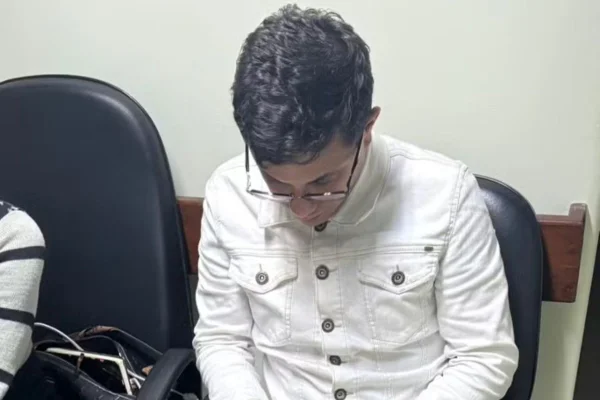 Homem com blusa branca e óculos está sentado, com cabeça abaixada - Metrópoles