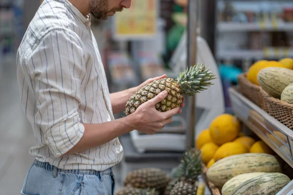 Homem segura abacaxi no mercado - Metrópoles