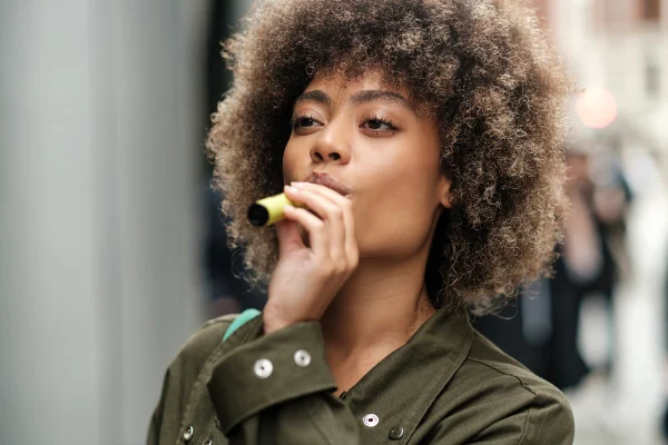 Foto colorida de mulher tragando o vape - Metrópoles