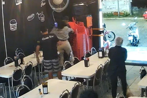 Imagem colorida de momento em que vítima luta tentando desarmar homem durante briga.