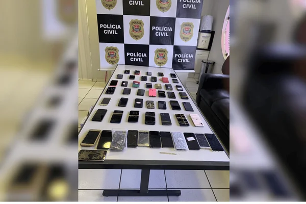Imagem colorida de uma mesa com diversos celulares apreendidos enfileirados - Metrópoles