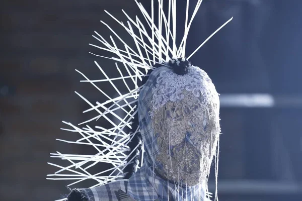 Modelo com o rosto tampado e spikes contornando a cabeça. na apresentação da marca João Pimenta, durante o SPFW 25 Anos