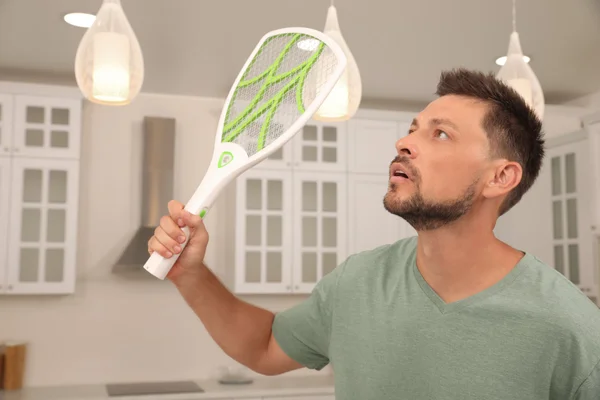 Foto mostra homem empunhando uma raquete mata-mosquitos