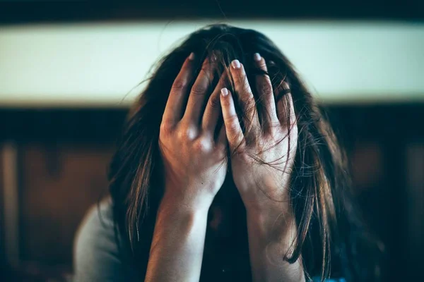 Mulher preocupada cobrindo o rosto com as mãos - Metrópoles