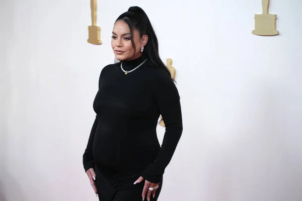 Atriz e cantora Vanessa Hudgens com vestido preto, cabelo preso e mostrando barriga de gravidez no tapete vermelho do Oscar - Metrópoles
