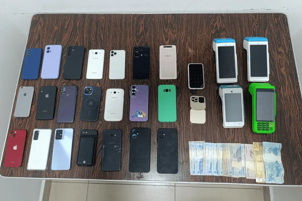 Imagem colorida de diversos celulares de origem duvidosa expostos em uma mesa de apreensão da Polícia Civil - Metrópoles