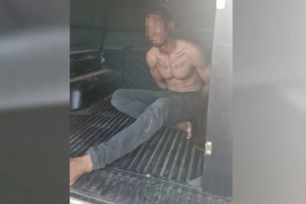 Homem negro preso em viatura da polícia, sem camisa e com calça jeans - Metrópoles