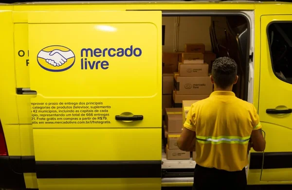Entregador coloca caixa dentro de van estilizada com o logo do Mercado Livre