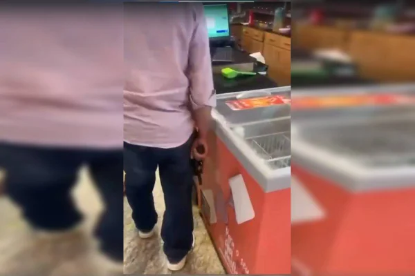 Foto colorida de homem em panificadora segurando um revolver