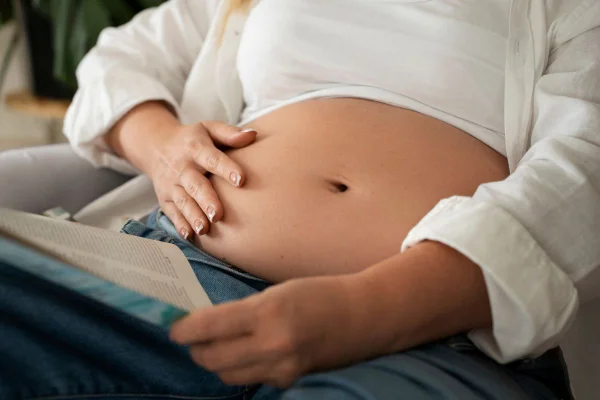 Mulher leva as mãos a barriga com inchaço abdominal e estufamento - Metrópoles