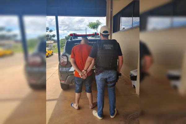 Policial conduz homem de camisa vermelha algemado