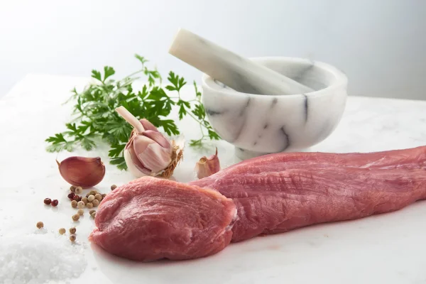 Imagem de parte do filé mignon suíno cru com temperos, na horizontal.