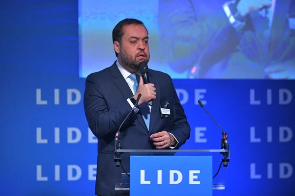 Fotografia colorida de homem de terno discursando em púlpito