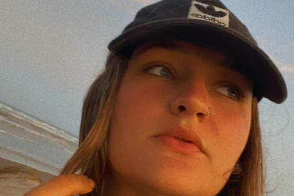 Imagem da jovem lais leichtweis olhando para o lado na frente da praia