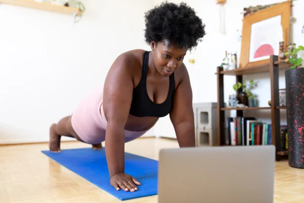 Imagem mostra mulher fazendo flexão de braços em um tapete azul - Metrópoles - flexões