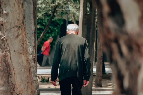 Imagem mostra um idoso de costas. Ele está caminhando e tem as costas encurvadas - Metrópoles