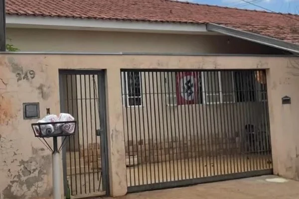 Imagem colorida de casa com bandeira com suástica nazista pendurada. Metrópoles