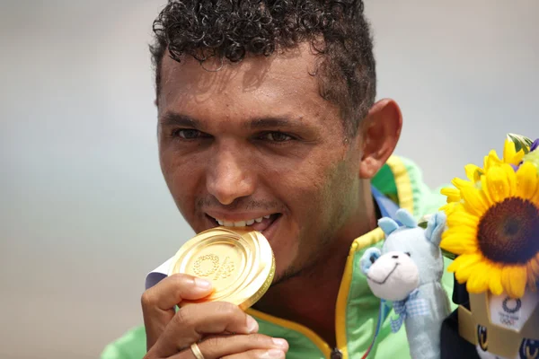 Isaquias Queiroz mordendo medalha de ouro