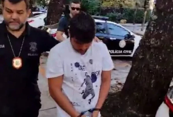 Em foto colorida, torcedor do Flamengo Jonathan Messias Santos da Silva é conduzido por policial civil, logo após ser preso no Rio de Janeiro - Metrópoles