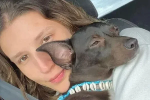 Foto colorida de mulher segurando um cão no colo - Metrópoles
