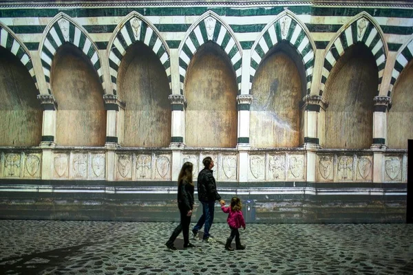 família observa projeção da cidade de florença em exposição sobre leonardo da vinci