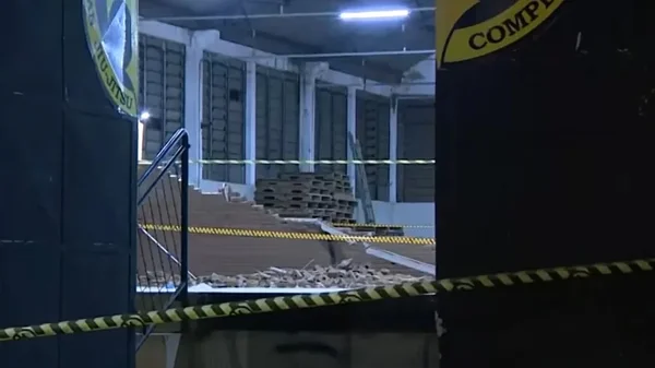Imagem de entrada de galpão com portas abertas; no interior, escombros de parede que desabou e feriu duas crianças - Metrópoles