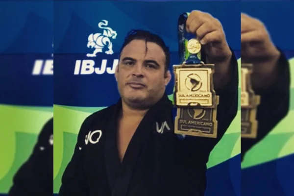 Homem de kimono preto segura medalha de ouro