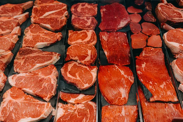 Foto colorida de vários tipos de carne de origem animal enfileiradas em uma superficie preta - Metrópoles.