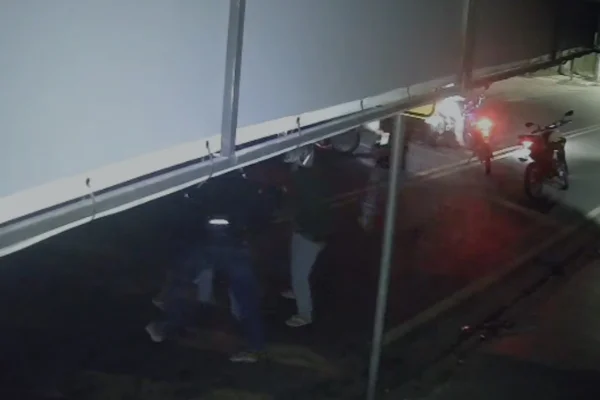 Imagem colorida de criminosos cercando policial morto. Metrópoles