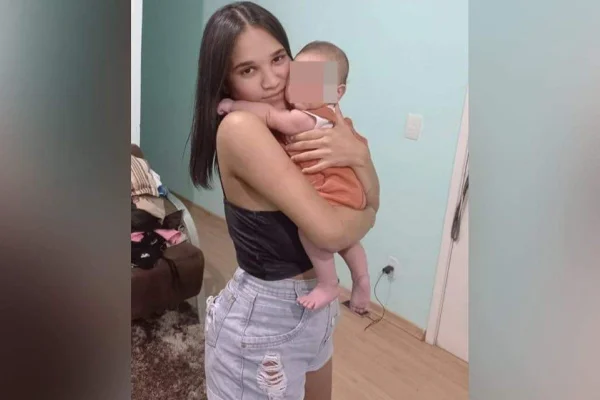 Imagem colorida de mulher com um bebê no colo. Metrópoles