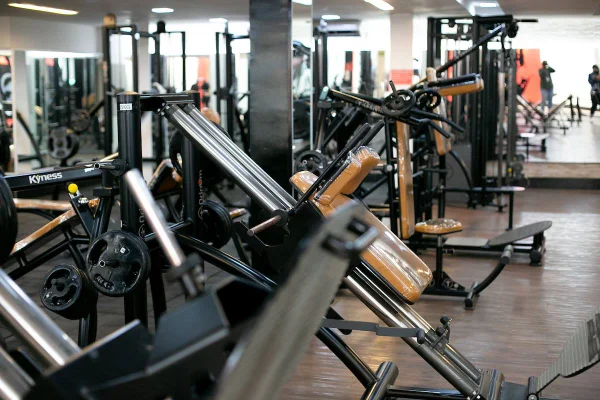 Foto colorida de uma academia repleta de equipamentos vazia