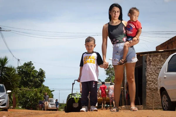 mulher em estrada com sol com duas crianças olhando para câmera