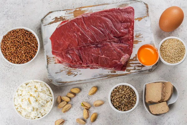 Foto coloridade de vários alimentos ricos em proteína, espalhados em uma mesa branca - Metrópoles.