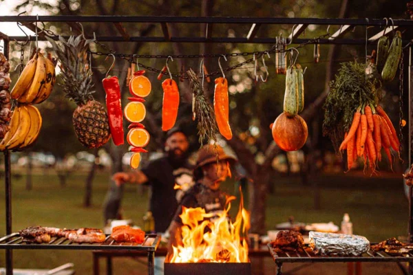 Parrilla com frutas, legumes e carne e duas pessoas ao fundo