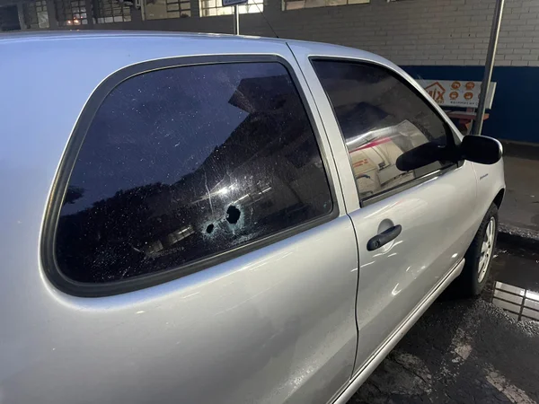 carro prato com duas marcas de tiros na janela traseira