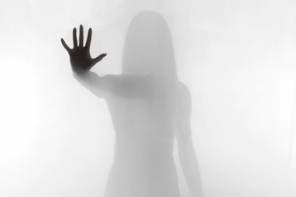 Imagem preta e branca de uma mulher com a mão destacada encostada em um véu