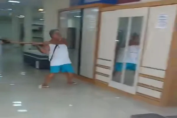 Imagem colorida de homem destruindo loja com machado - Metrópoles