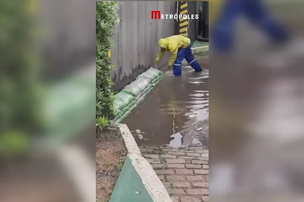 Imagem colorida mostra funcionário da prefeitura de Porto Alegre contendo vazamento de água do Lago Guaíba