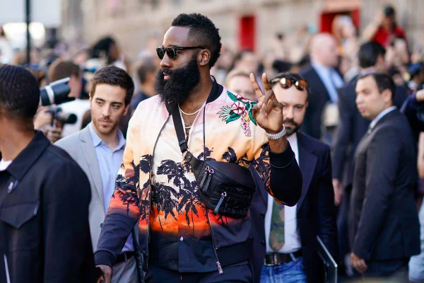 Jogador negro com barba volumosa usa casaco com estampa de árvores na tonalidade laranja