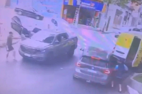 Imagem de câmera de segurança mostra homem ao lado de picape apontando arma para homem ao lado de um T-Cross que roubava produtos de uma van - Metrópoles