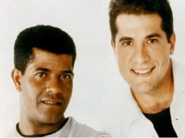 Homem preto e homem branco posam em fundo branco - Metrópoles