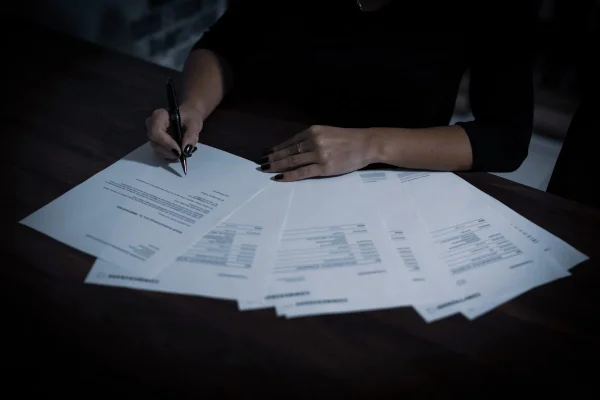 Pessoa conferindo informações em vários documentos de papel