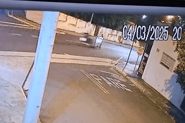 Imagem colorida de uma câmera de segurança mostra uma motocicleta indo de encontro ao idoso atravessando a rua com um carrinho de pipoca - Metrópoles